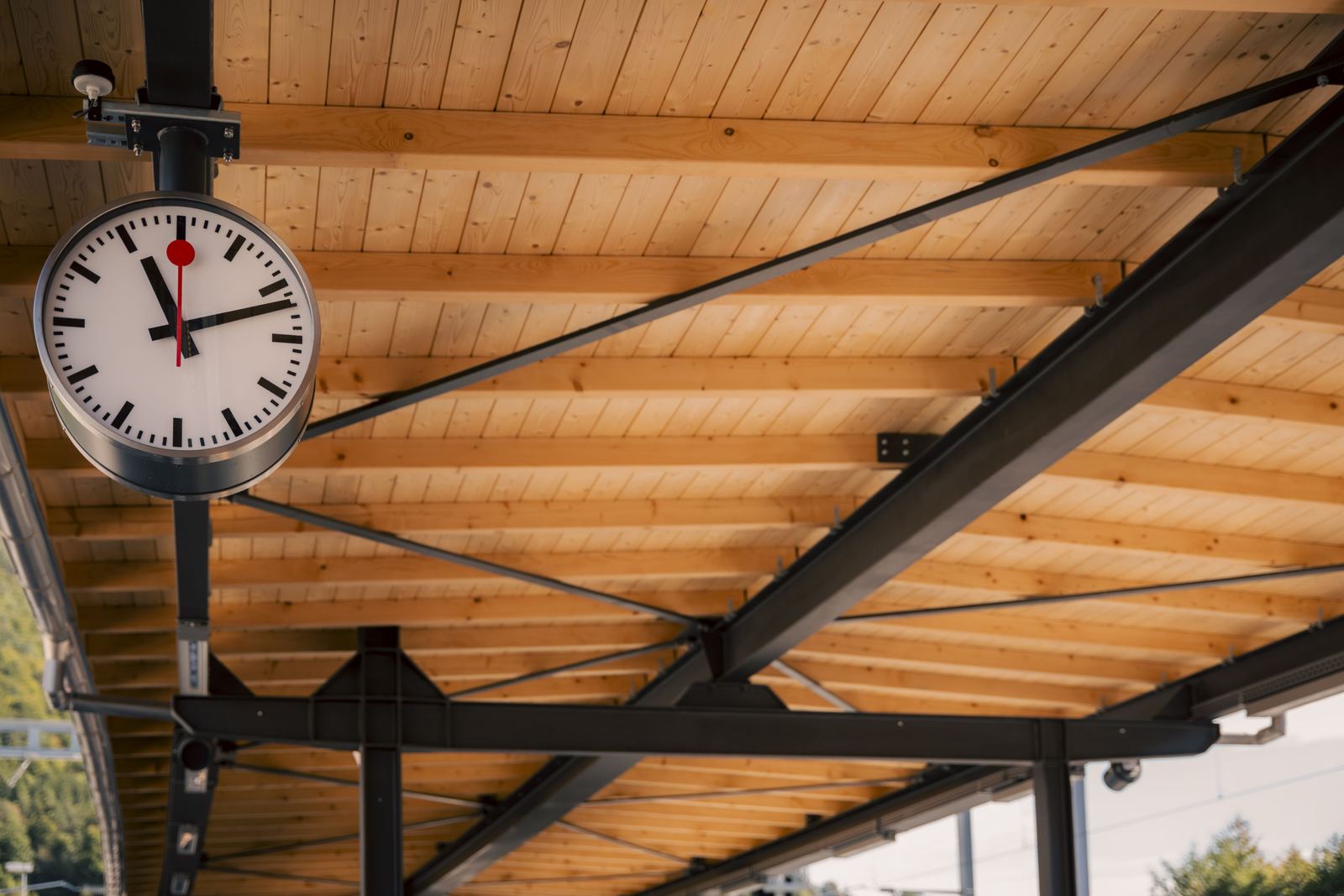 Horloge de gare sous une charpente métallique à sous-face en bois