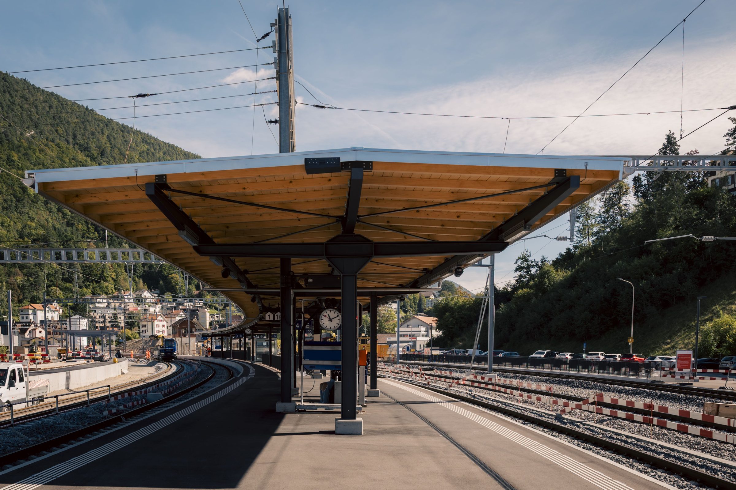 Couvert de quai à charpente métallique et sous-face en bois, gare CFF entourée de montagnes